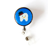 Lilac and Friends dental badge reel with white tooth dressed as a snowman complete with face and black top hat on blue background and snow flurries. .Frosty dental badge reel for dental professionals by Lilac Paper.