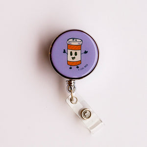 Lilac and Friends Happy Pills dental badge reel with smiling orange pill bottle on a purple background. Happy Pills dental badge reel for dental professionals by Lilac Paper.