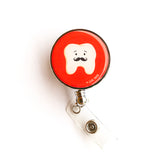 Lilac Paper, Lilac and Friends heavy duty badge reel for dental professionals with enamel dome and metal casing. Front side features a tooth with mustache face on a red background. Red badge reel.