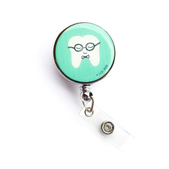  Lilac and Friends dental badge reel with smiling white molar wearing glasses and tiny bowtie on a mint green background. Nerd Alert dental badge reel for dental professionals by Lilac Paper.